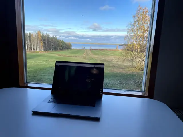 Laptop on a desk by a window overlooking the field and lake